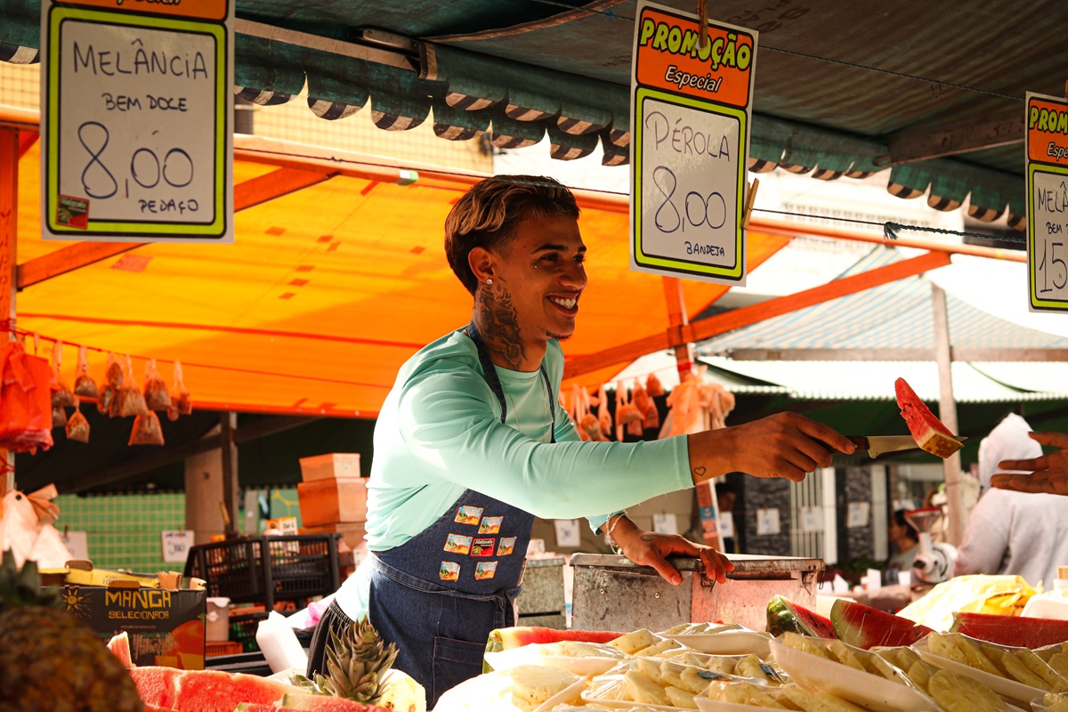 Na rua Manoel Gaya, no bairro da Vila Nova Mazzei, Guilherme Henrique, 19, é conhecido como Mc Doze, e trabalha em uma barraca de frutas ao lado do pai
