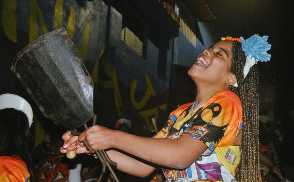 A jovem tocando instrumento no ensaio do Baque Atitude